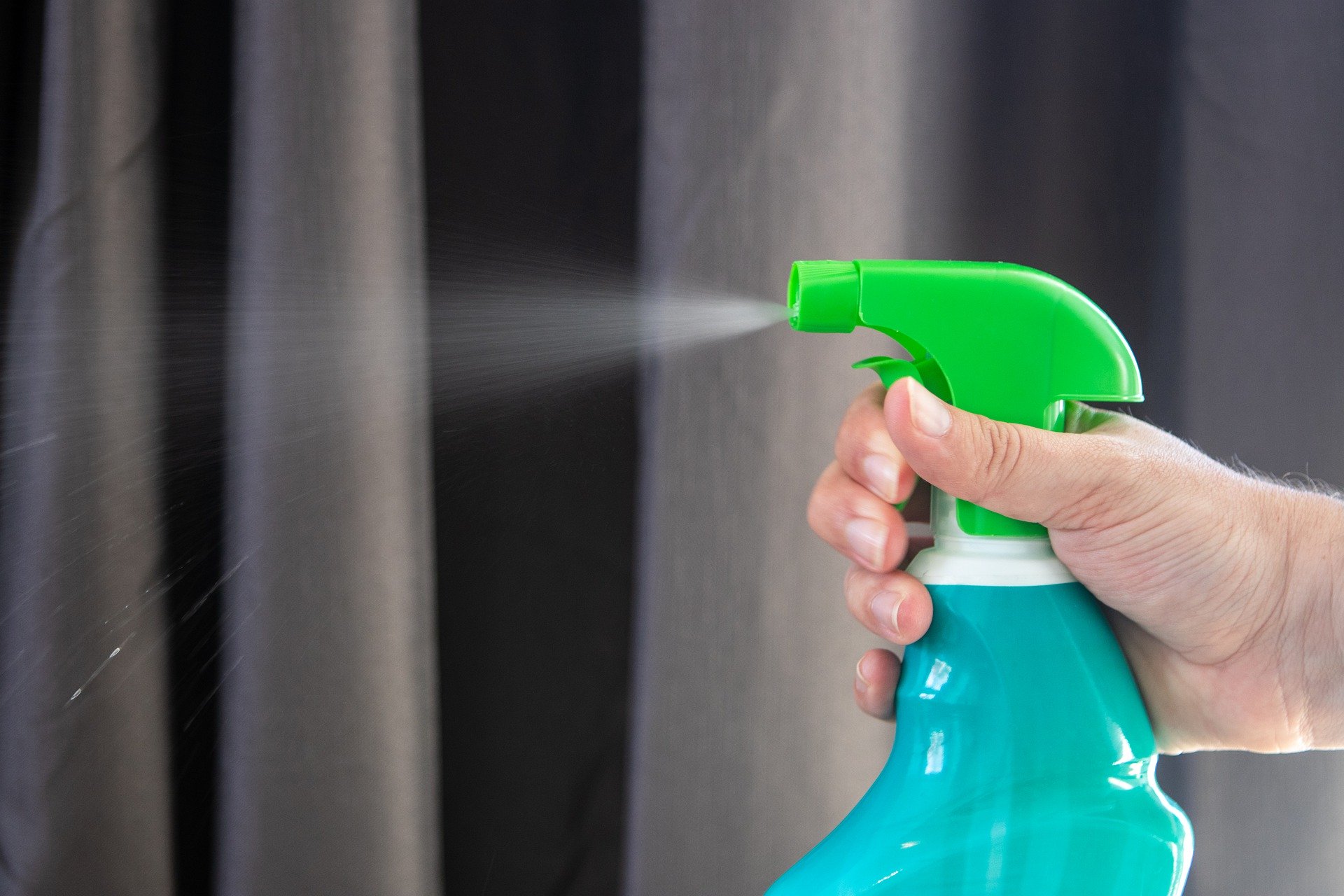 hand spraying disinfectant on a wall